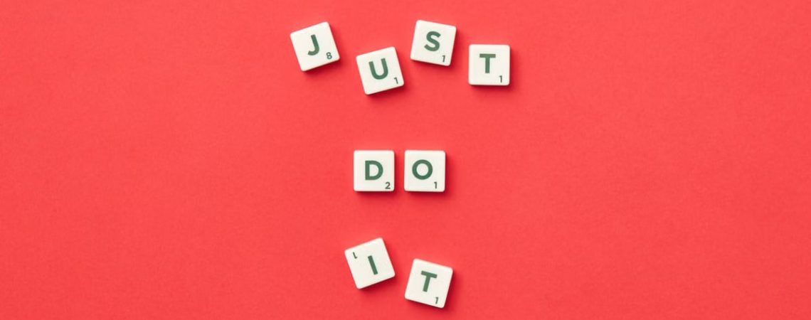 Motivational phrase 'Just Do It' spelled with Scrabble letters on a red background.